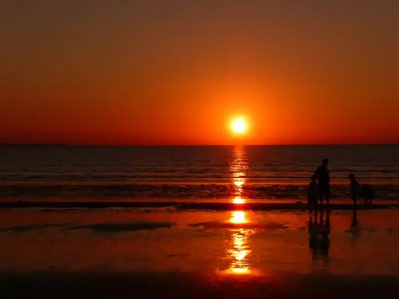 Sunset over the Indian Ocean at Mindil Beach Sunset Market in Darwin, with visitors heading toward the shoreline