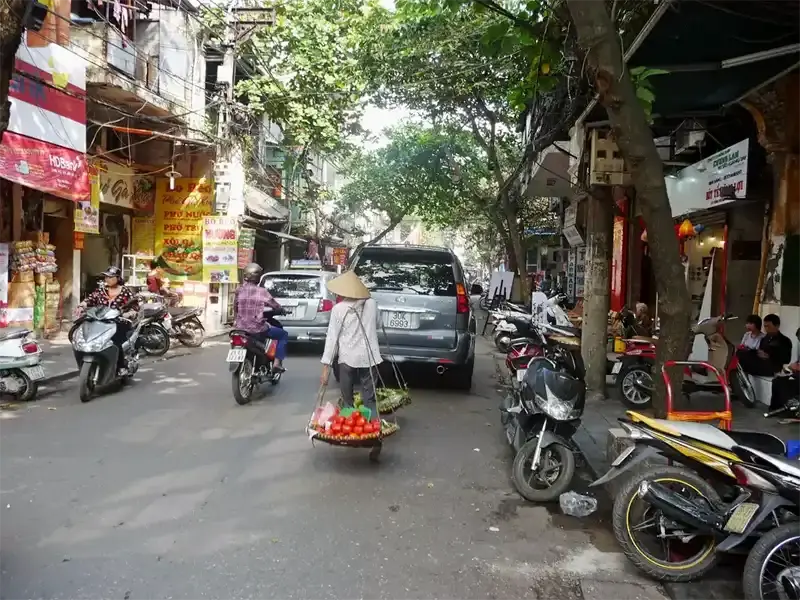 Vibrant street scene in the Hanoi Old Quarter near Hoan Kiem Lake, Vietnam, showing busy markets and traditional architecture.
