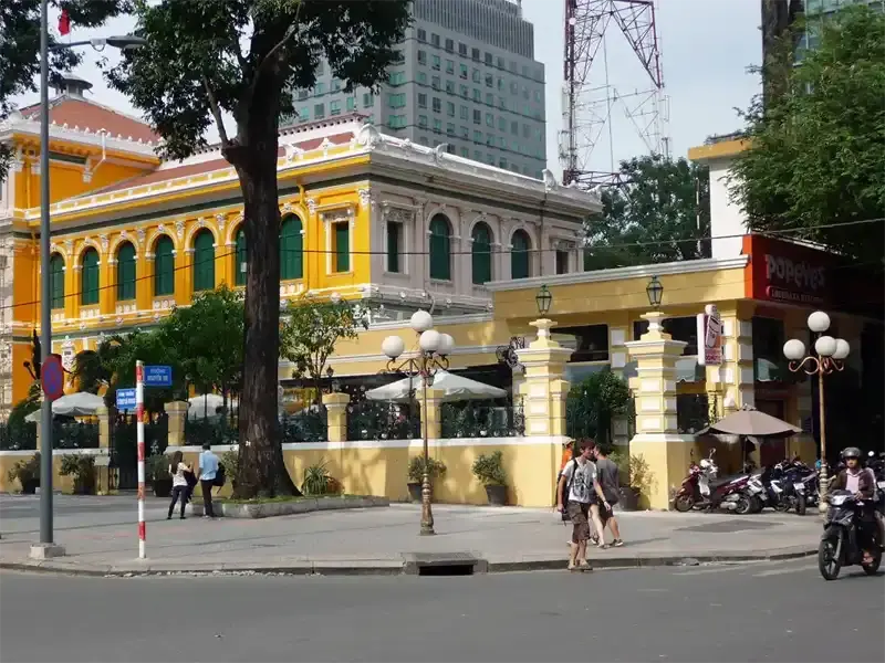 Exterior view of the historic Saigon Central Post Office in Ho Chi Minh City, showing its French colonial design and pale yellow exterior