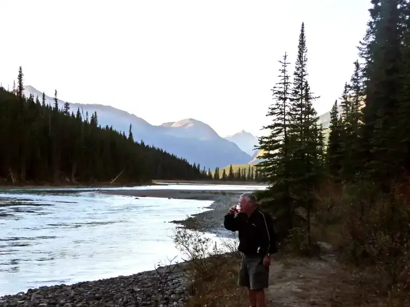 Secluded riverside RV campsite along the Icefields Parkway in the Canadian Rockies, surrounded by wilderness and flowing river.