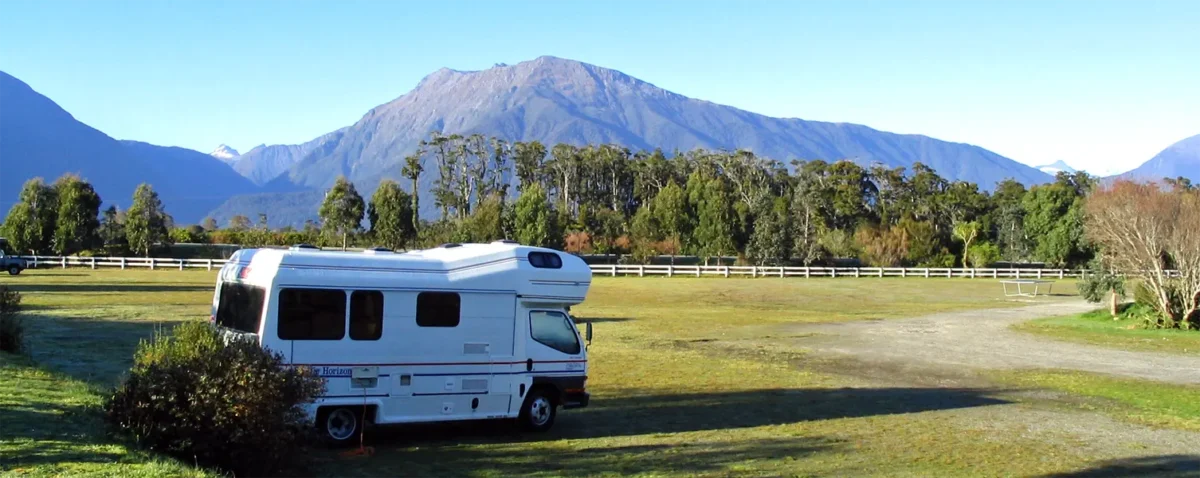 New Zealand South Island Travel Guide: Staying alone at a caravan park with mountain background, South Island New Zealand