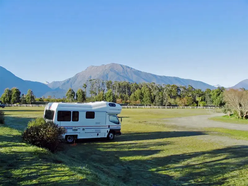Haast River Motels & Holiday Park NZ with background of the spectacular mountain ranges bordering Mount Aspiring National Park.
